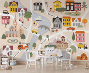 Children's map of a town with colorful houses, roads, and vehicles on a wall.