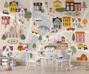 Children's map of a town with colorful houses, roads, and vehicles on a wall.
