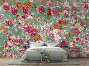 Bedroom with colorful floral wallpaper and a bed with gray bedding and a multicolored throw blanket.