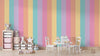 Children's room with pastel striped wall, toys, and furniture.