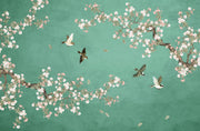 A decorative wall mural or wallpaper featuring a teal green background with traditional-style cherry blossom branches in white and pink, flying birds, and scattered falling petals.