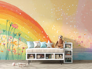A children's bedroom scene featuring a colorful rainbow and wildflower wall mural. A low white bench with storage cubbies holds a beige cushion and decorative pillows, next to a small gray side table.