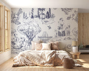 A styled bedroom featuring a large wall mural with a classic French toile de Jouy print in dark blue-gray on a warm off-white background. The room is furnished with a bed, beige bedding, wooden flooring, and a wooden slat accent wall.