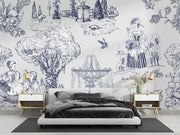 A styled bedroom featuring a large wall mural with a blue and white toile de Jouy illustration pattern. The room includes a low white platform bed with dark gray bedding, two matching light wood nightstands with gold lamps, and a dark gray rug on a light wood floor.