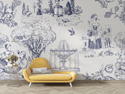 A styled interior scene showing a yellow upholstered lounge chair in front of a wall covered in a blue toile-style mural with floral and architectural illustrations. A small side table with flowers sits to the left, and light wood flooring is visible below.