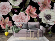 A styled living room featuring a large-scale floral wallpaper mural with pink, white, and green flowers on a black background, behind a lavender sofa with decorative pillows and a green throw blanket.