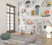 Children's room with colorful wall mural of vehicles and buildings, featuring a rug and bean bag on the floor.