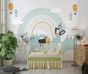 Nursery room with crib, wall mural of mountains and hot air balloons, and wooden dresser.