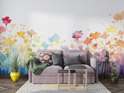 Living room with a gray sofa, colorful floral wall mural, and decorative plants.