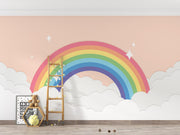 Colorful rainbow mural on a wall with a wooden ladder and toys below.
