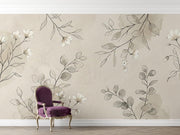 A styled interior scene showing a beige wall with a floral wallpaper pattern in soft gray and white, plus a purple upholstered armchair with gold legs placed in front of the wall.