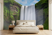 Skógafoss waterfall wall mural behind a beige upholstered bed in a bedroom mockup