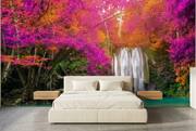 Pink forest waterfall wall mural behind a cream upholstered bed in a bedroom mockup