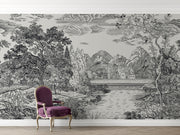 A large-scale black and white scenic wallpaper mural featuring a detailed landscape with trees, mountains, a river, and small houses, styled in a room setting behind a purple velvet armchair.