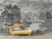 A large-scale black and white scenic wallpaper mural featuring a detailed landscape with mountains, trees, clouds, and a lake, styled in a room setting behind a modern yellow armchair.