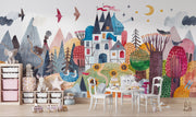 Colorful mural of a whimsical village scene with houses, trees, and animals on a wall.