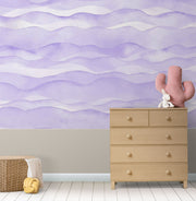 Purple wave-pattern wall mural with soft flowing designs, decorating a cosy children’s nursery.