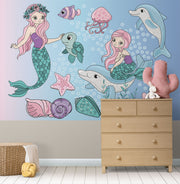 Whimsical underwater-themed mural with pastel mermaids, dolphins, turtles, jellyfish, and fish set against a blue bubble-filled background in a cozy kids' room.