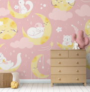 Moon-and-cat-themed wall mural featuring pastel pink tones, crescent moons, sleepy cats and stars, decorating a cozy nursery.