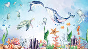 Underwater-themed kids wall mural with watercolor illustrations of a whale, turtle, dolphin, jellyfish, seahorses, coral, and fish in a nursery setting.