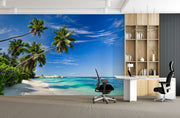Palm oasis wall mural featuring tall palm trees, white sand, and turquoise waters under a bright blue sky, creating a refreshing workspace atmosphere.