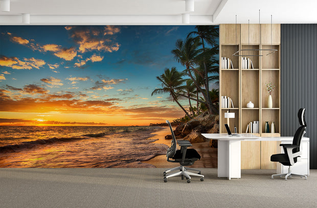 Golden sunset wall mural with palm trees, vibrant sky, and tranquil ocean waves, creating a relaxing and coastal living room ambiance.