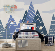 Adventure Peaks wall mural featuring abstract mountain shapes in blue and peach tones with a sun and clouds, styled in a boy’s bedroom.