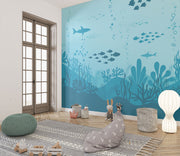Underwater-themed wall mural featuring silhouettes of sharks, fish, and coral reefs in varying shades of blue, perfect for a calming and playful kids’ room.