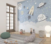 Space-themed wall mural with rocket, UFOs, planets, and constellations on a blue sky background—ideal for kids' room décor.