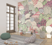 Desert bloom wall mural with hand-drawn cacti, succulents, and rolling hills in pink, green, and cream tones, creating a bold and artistic bedroom backdrop.