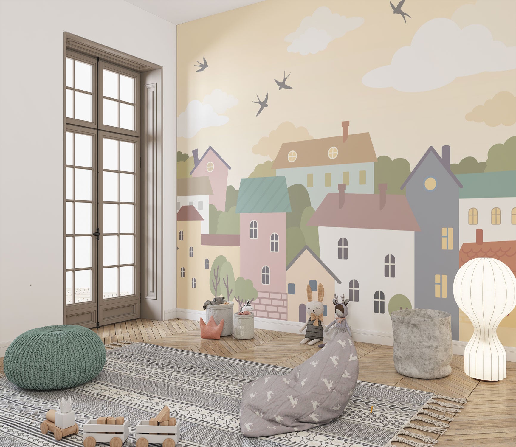 Whimsical village wall mural featuring pastel houses, trees, clouds, and flying birds, styled in a cozy and creative kids’ playroom.