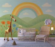 Nursery wall with pastel rainbow mural, green hills, colorful flowers, and a crib with plush toys in front.