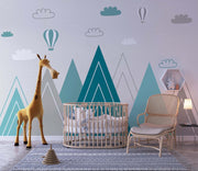 Modern geometric mountain wall mural in teal and grey with hot air balloons and clouds, styled in a contemporary nursery.