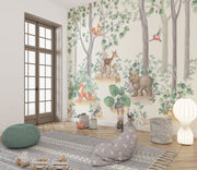 Woodland-themed wall mural featuring a bear cub, deer, squirrel, birds and lush green trees, decorating a cozy children's bedroom with a wooden house bed and natural decor.