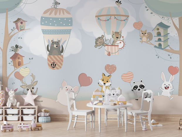 Nursery wall mural with pastel-colored forest animals flying in hot air balloons, surrounded by trees, clouds, and heart-shaped balloons